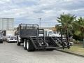 A 1998 Freightliner FL80 truck with a flatbed and ramps at the rear, featuring dual rear wheels and a sturdy black frame