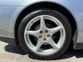 A close-up of a silver Ferrari wheel showcasing a five-spoke alloy rim, yellow center cap with the Ferrari logo, and a Michelin tire with visible tread pattern