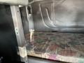 An interior sleeping berth of a 2009 Peterbilt Highway truck with a floral patterned mattress and a grey cabin wall