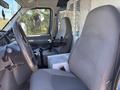 Interior of a 2008 Ford E-350 showing the driver's seat and passenger seat with a console in between and a mounted equipment holder on the dashboard