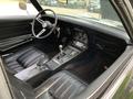 Interior of a 1972 Chevrolet Corvette featuring black leather seats a central console with controls and a leather-wrapped steering wheel