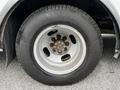 A close-up view of a silver wheel with a round rim and multiple lug nut holes attached to a black tire