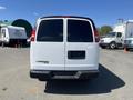 A white 2012 Chevrolet Express van is parked with its rear facing the viewer, featuring large tinted windows and a simple tailgate design