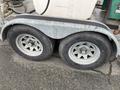 A dual flat deck trailer with two wheels and a metallic frame designed for hot water weed control with a large container on top