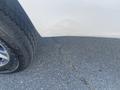 A 2014 Ford F-250 SD with noticeable damage on the side panel near the rear wheel and a close-up of the tire tread