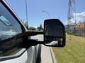A 2023 Ford F-550 side mirror reflecting part of the vehicle and a hand holding a camera