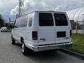 A white 2014 Ford Econoline van parked on the street with tinted windows and chrome accents on the rear bumper