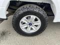 A close-up of a silver alloy wheel with a black all-terrain tire mounted on a 2017 Ford F-150