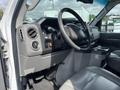 Interior of a 2009 Ford Econoline featuring a steering wheel dashboard controls and a center console with cup holders