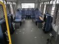 A 2012 Chevrolet Express van interior featuring rows of blue fabric seats with patterned curtains on the windows and minimalistic flooring