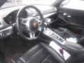 Interior view of a 2016 Porsche Boxster featuring black leather seats and a sport steering wheel with a Porsche emblem