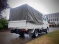 A white 2003 Toyota Toyoace truck with a covered cargo bed, featuring a grey tarpaulin and visible Toyota branding on the rear