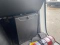 A metal storage box labeled GIGARON is mounted on the interior wall of a van beside a fire extinguisher and a piece of gray fabric