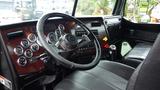 Interior of a 2019 Western Star Trucks 4900 featuring a black leather seat a steering wheel and various gauges and controls on a wooden dashboard