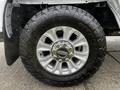 Close-up of a metallic silver wheel and black tire from a 2020 Ford F-350 SD with bold tread patterns and chrome accents on the wheel rim