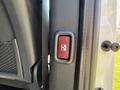 A close-up view of the door handle of a 2023 Mercedes-Benz Sprinter featuring a red button with a cross symbol