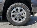 A close-up view of a chrome wheel rim on a 2022 RAM 3500 featuring a large all-terrain tire with a rugged tread design and the brand logo visible on the sidewall