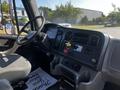 Interior view of a 2004 Freightliner M2 truck featuring a driver's seat dashboard with controls and gauges