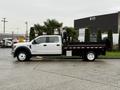 A 2022 Ford F-550 truck with a flatbed, featuring a white cab and black flatbed with red and white reflective striping