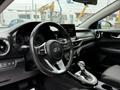 Interior of a 2021 Kia Forte featuring a steering wheel with controls a digital dashboard and a central infotainment display