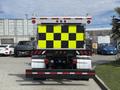 A 2016 Freightliner 108SD truck with a rear design featuring bright yellow and black reflective squares and multiple lights on top