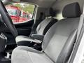 Interior view of a 2020 Nissan NV200 featuring two front seats with black fabric upholstery and a center console between them