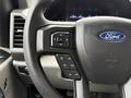 Steering wheel of a 2021 Ford F-550 featuring control buttons for settings and menus with a blue Ford emblem in the center
