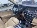 Interior of a 2009 BMW X5 featuring a leather steering wheel beige leather seats and a central dashboard with audio controls and a gear shifter