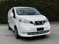 A white 2020 Nissan NV200 van is parked with its front angled slightly towards the viewer showcasing its distinctive grille and headlight design