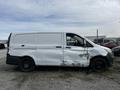 A 2018 Mercedes-Benz Metris with a damaged side panel and missing hubcap parked in a gravel area