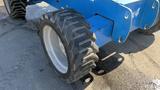 Close-up of a 2008 Genie S-65 Boom Lift tire showing deep treads and a blue metal framework connected to the machine