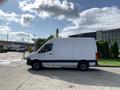 A white 2021 Mercedes-Benz Sprinter van parked with its side view visible showcasing its elongated body and black accents on the wheels and lower section