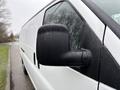 A close-up view of the side mirror of a 2014 GMC Savana, showcasing its black exterior and rain droplets on the surface