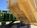 A yellow 2022 TerraMac tracked dump with its bed raised showcasing hydraulic lift arms and internal components