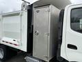 A white 2014 Hino 195 truck with a metallic storage compartment attached to the side of the bed