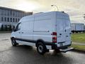 2012 Mercedes-Benz Sprinter van with a white exterior and a rear loading step parked on a street with a commercial building in the background