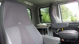 Interior of a 2012 International 7400 featuring two upholstered seats with a textured pattern and a small table in the foreground.