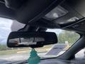 A rearview mirror of a 2017 Dodge Challenger showing a small green air freshener hanging below it