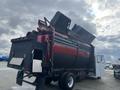 A 2009 Hino 338 garbage truck with a red and black body featuring an open rear compartment for loading waste