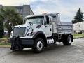 A white 2011 International WorkStar dump truck with a front-mounted plow and a metal dump bed parked in a driveway