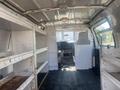 Interior of a 2009 Ford Econoline van showing empty shelving on both sides and a driver’s seat with a partition in the front