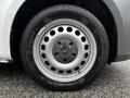 A close-up of a silver wheel of a 2023 Mercedes-Benz Metris featuring a circular design with multiple holes in the rim and a black tire