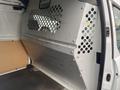 Interior of a 2017 Ford Transit Connect cargo van featuring a metal bulkhead with circular perforations and a wooden floor