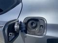 Close-up of the fuel cap and filler neck of a 2017 Acura TLX with the cap open and a gas nozzle adapter visible inside
