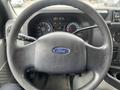 A steering wheel with a Ford logo and dashboard gauges of a 2010 Ford Econoline van are visible in the foreground