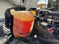 A translucent orange coolant reservoir attached to a 2014 International TerraStar engine with visible hoses and caps