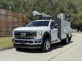 A 2023 Ford F-550 with a utility body equipped with a crane and various compartments for tools and equipment