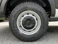 A close-up of a black tire mounted on a wheel with silver accents showcasing rugged tread designed for off-road traction