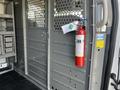 A 2016 Ford Transit van interior with a mounted fire extinguisher attached to the wall and storage compartments on the left side