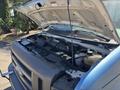 A 2008 Ford E-350 with its hood raised revealing the engine compartment and various components inside